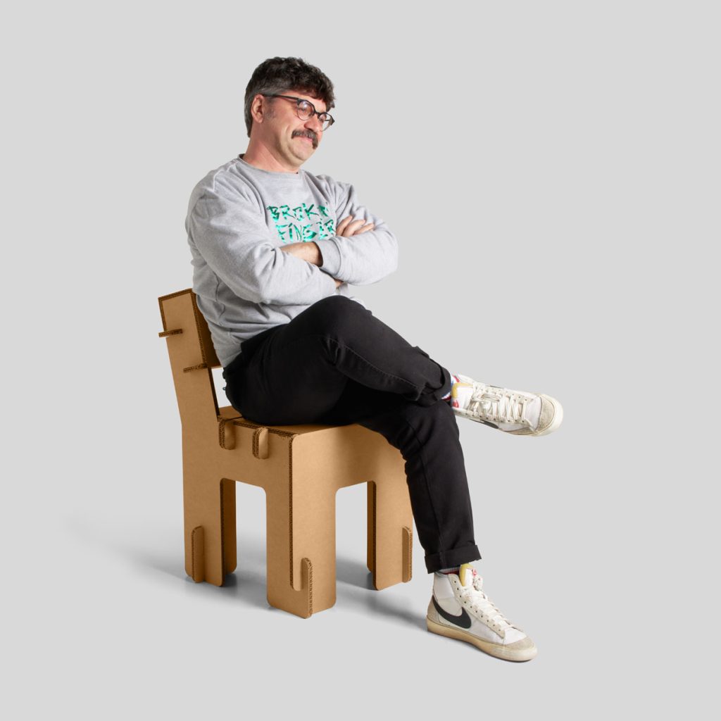 Silla en cartón Taray. Acabado kraft. Vista general con persona.