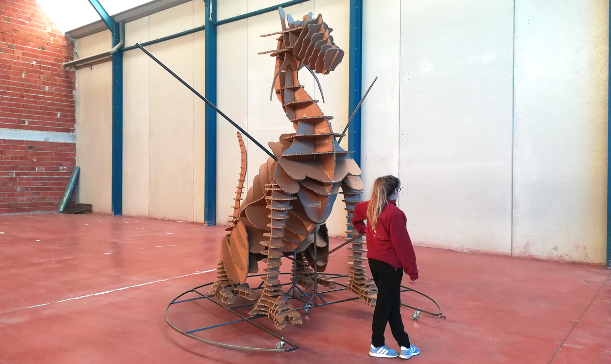 dragón gigante de cartón al lado de una mujer