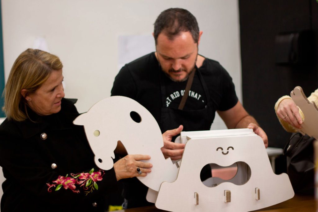 Dos alumnos del taller montando un caballito de cartón