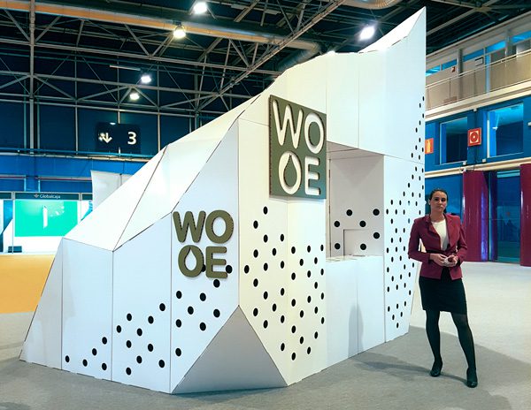 Trabajadora de World Olive Oil frente al stand de cartón