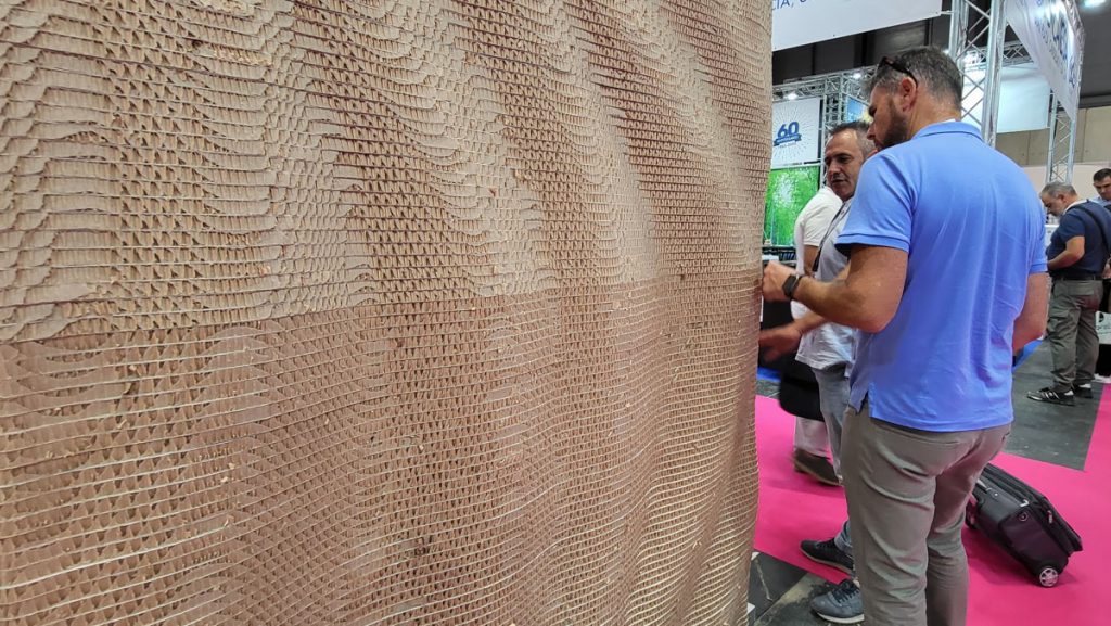 Visitante del stand tocando el muro paramétrico de cartón