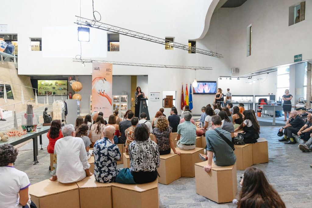 Público sentado sobre módulos de cartón